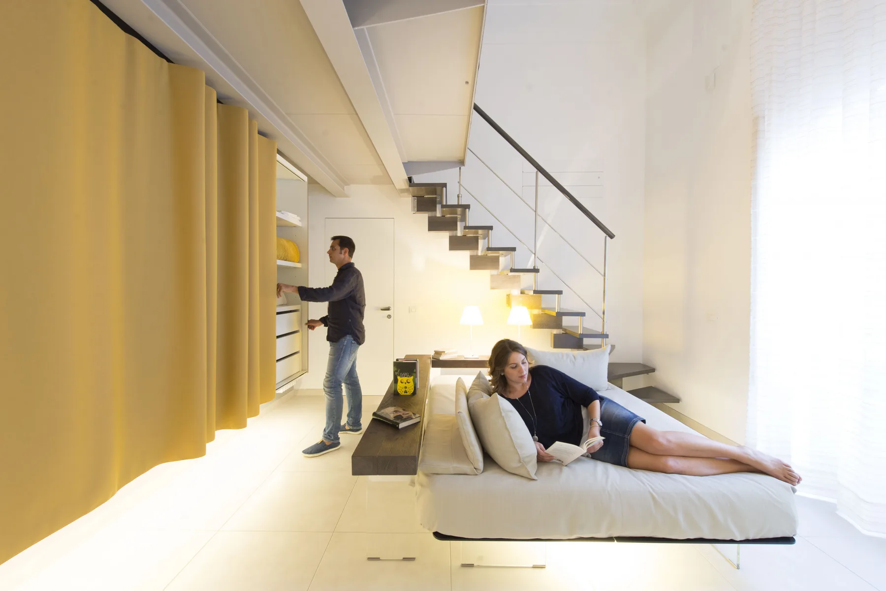 Una sala luminosa con asientos bajo una escalera abierta.