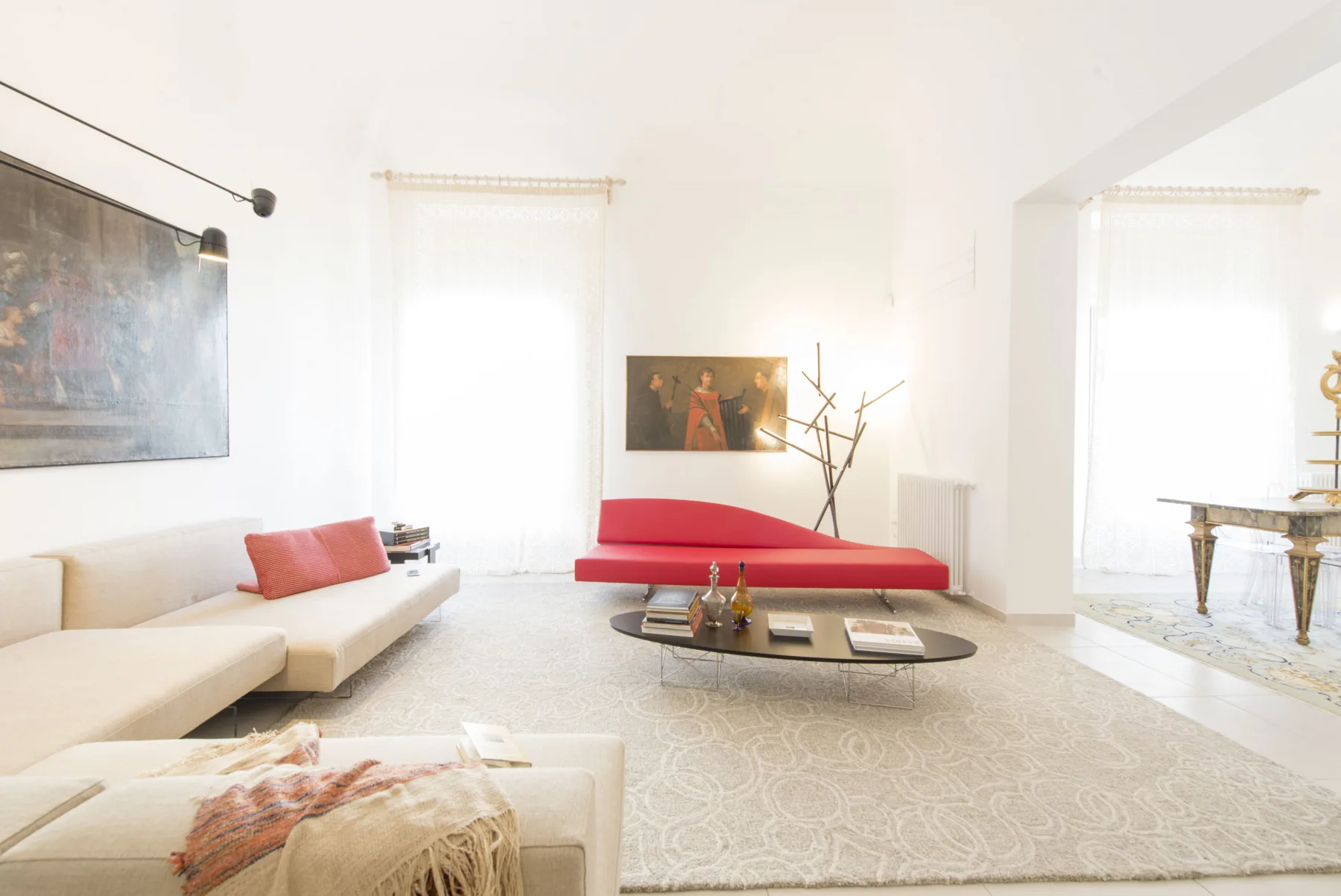 Una sala de estar luminosa con un sofá rojo bajo y una alfombra clara.