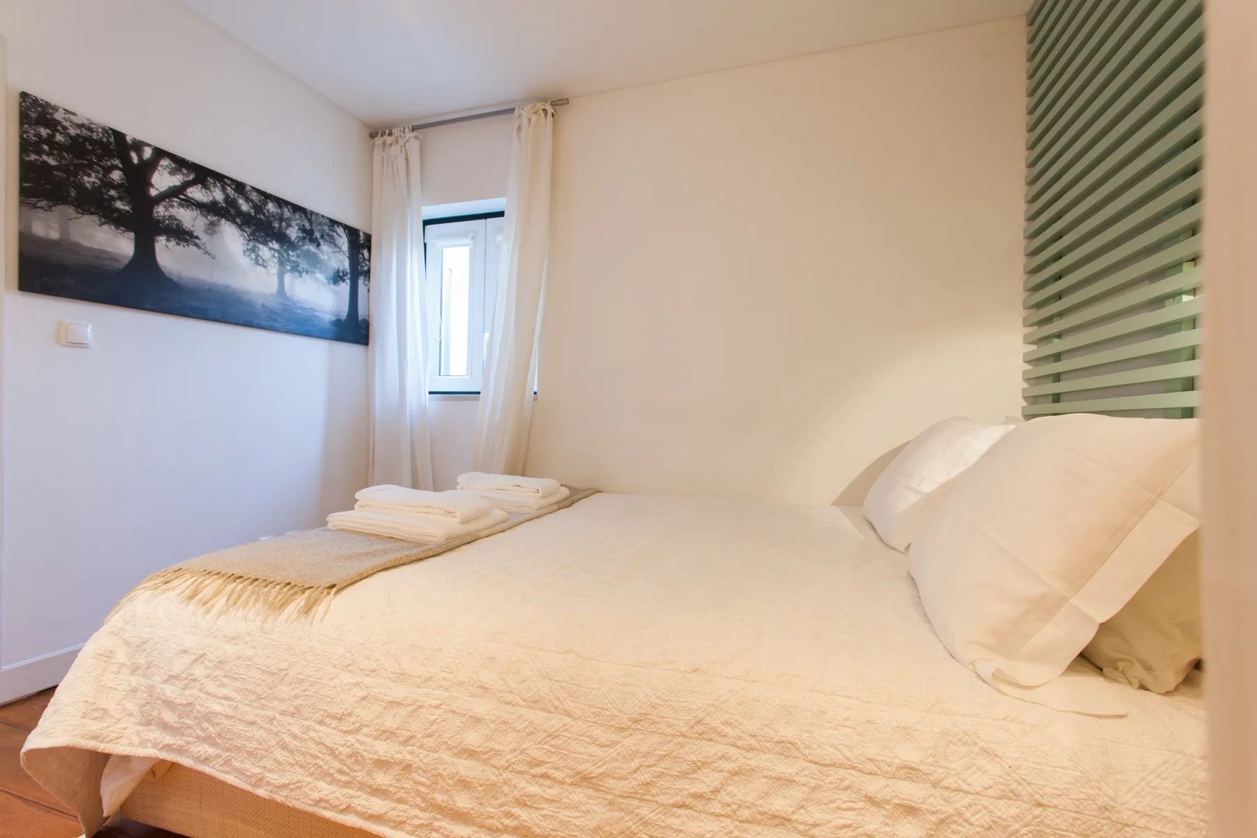 A bright bedroom with a neatly made bed and a window.