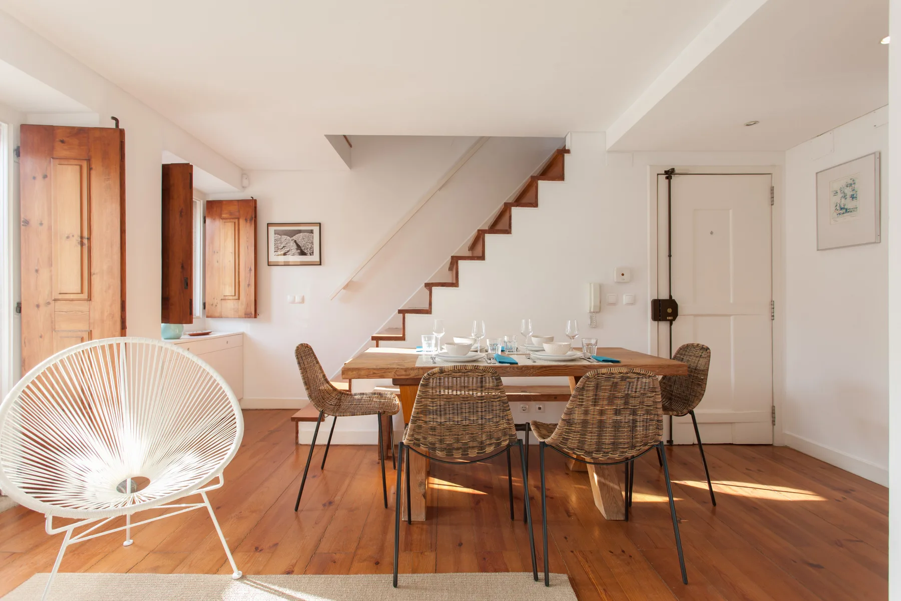 A bright dining area with a wooden table and a staircase.