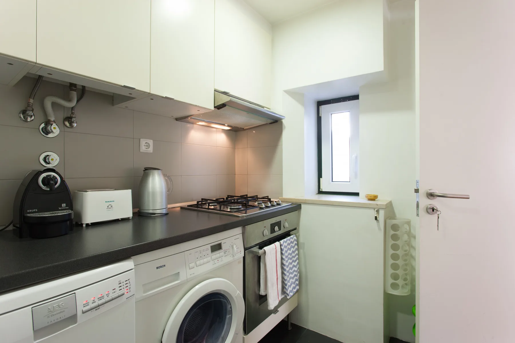A compact kitchen with a countertop, cooking hob, and washing machine.