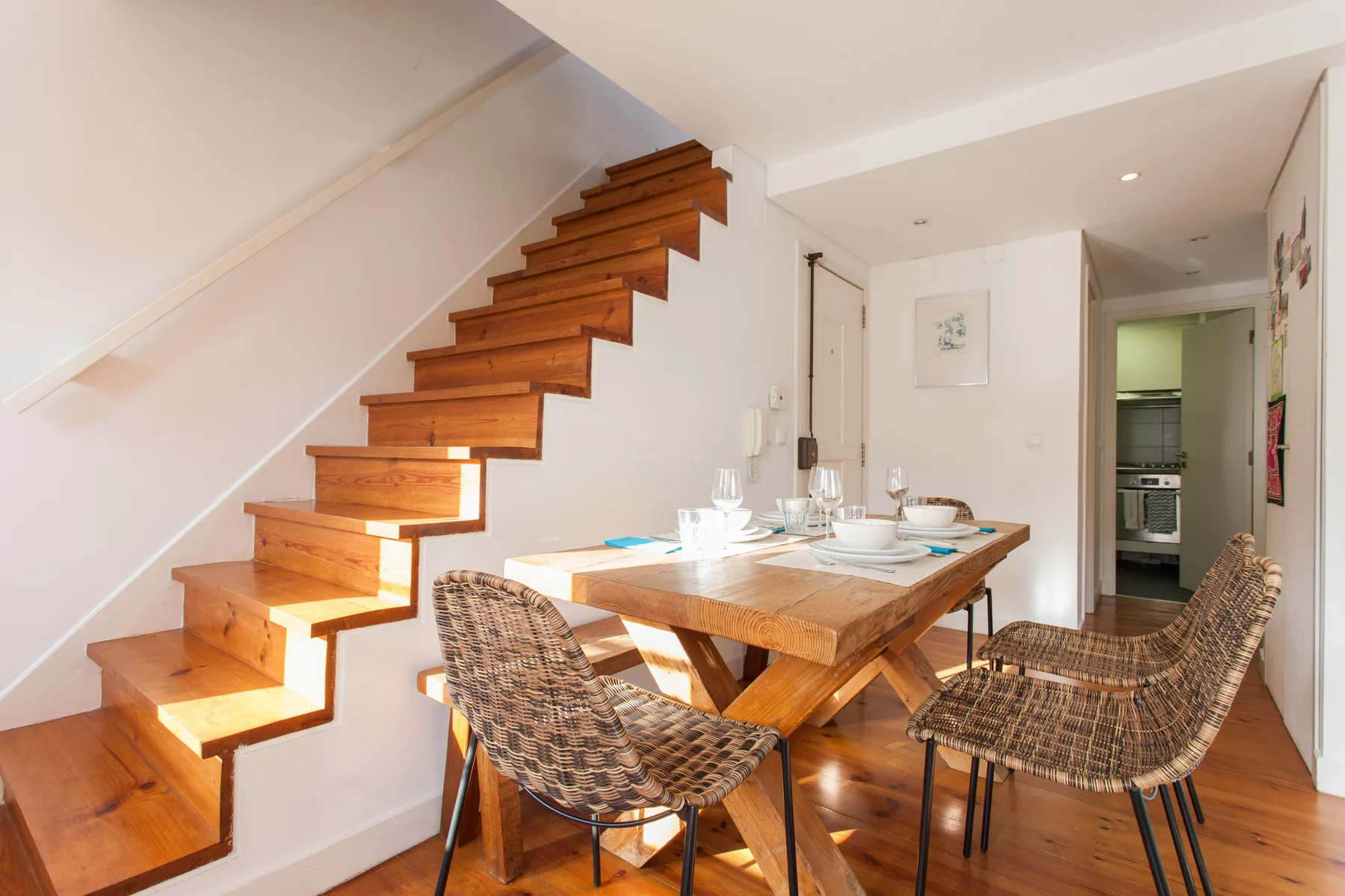 A dining area with a wooden table and chairs beside a staircase.