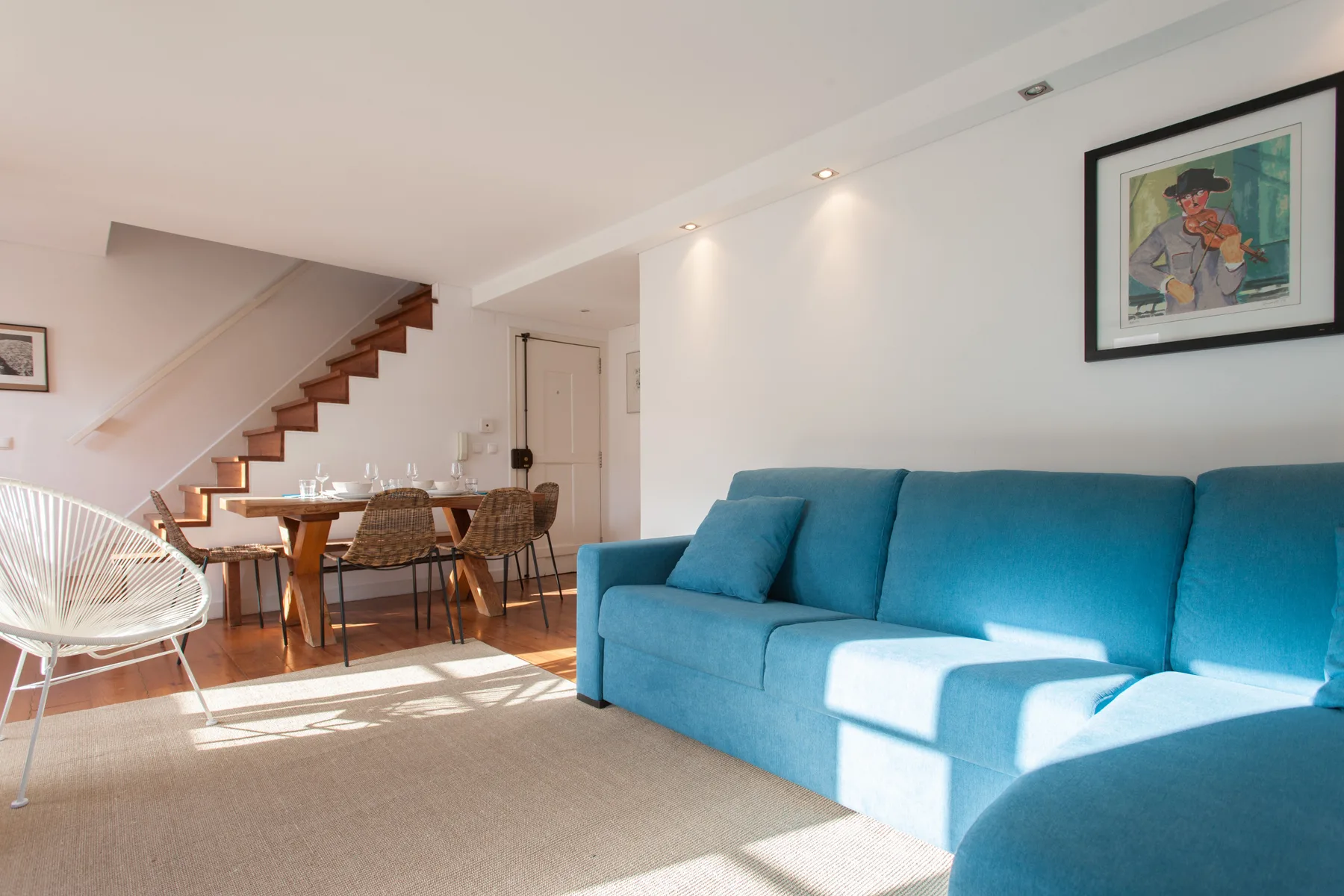 Una luminosa sala de estar y comedor tiene asientos azules y una mesa de madera.