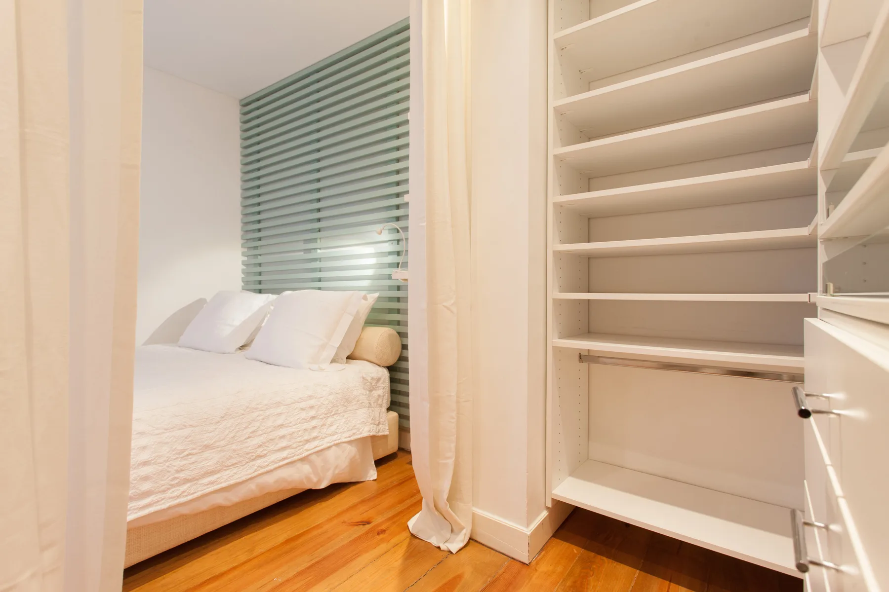 A bedroom with a bed beside an open built-in closet.