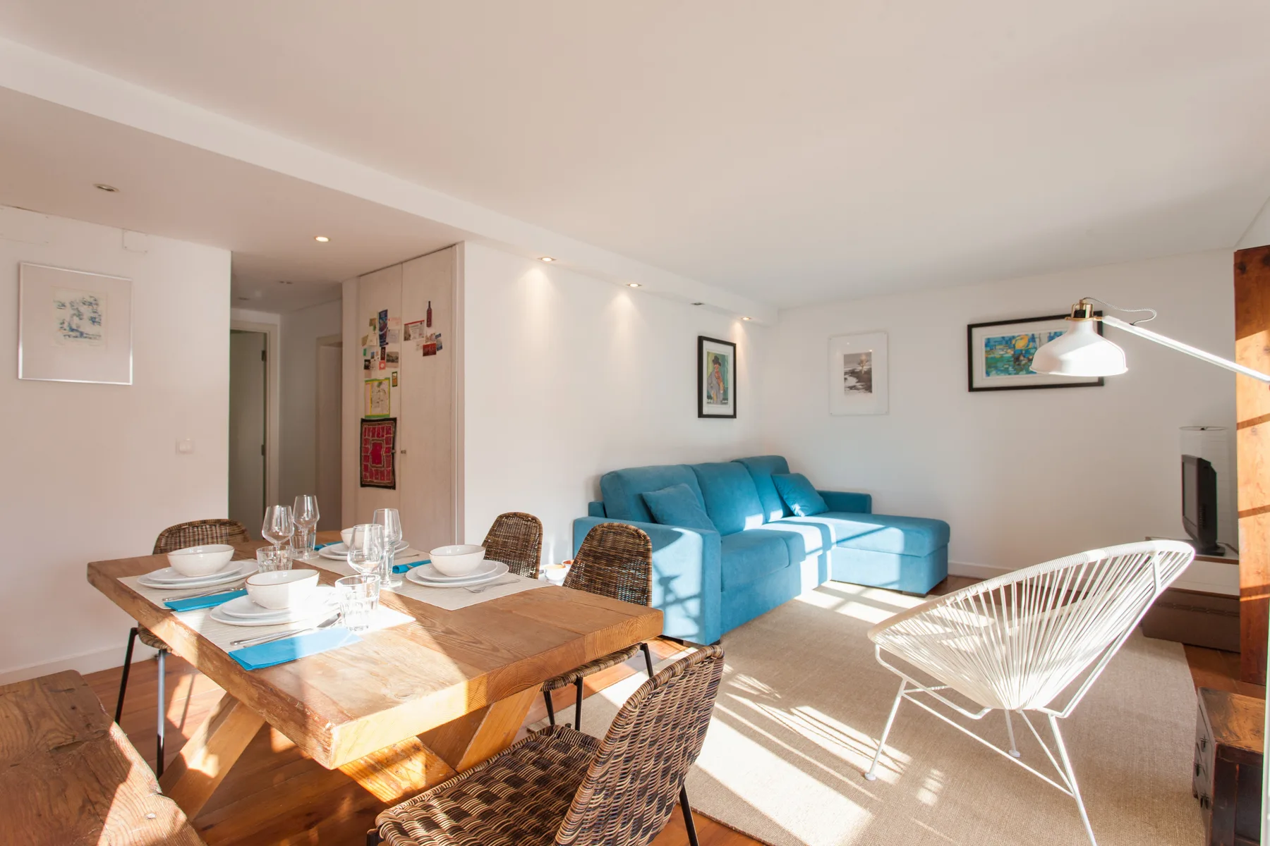 A bright living and dining area with blue seating and a wooden table.