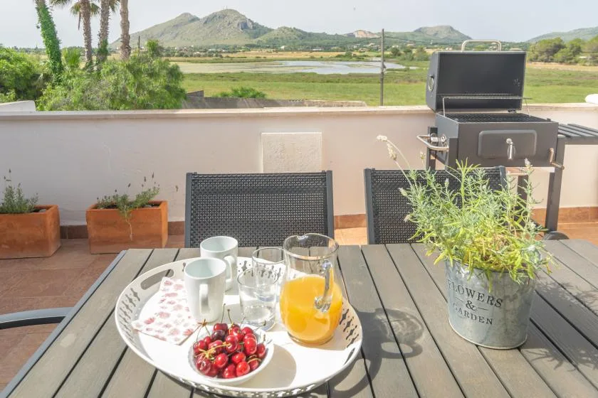 A patio table set with breakfast overlooks green fields and distant hills.