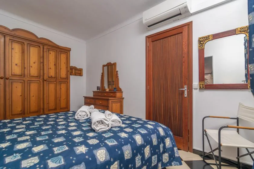A bedroom with patterned bedding, wooden storage furniture, and a mirror.