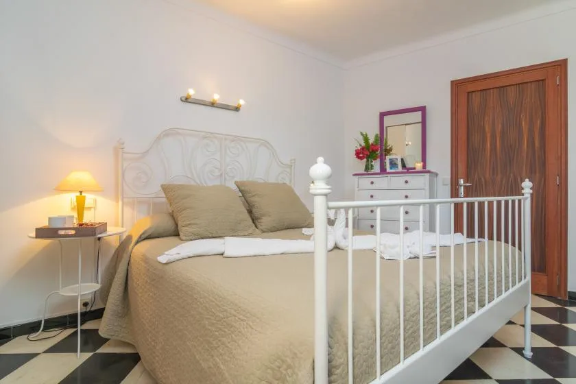 A bedroom with a double bed, bedside table, and chest of drawers.