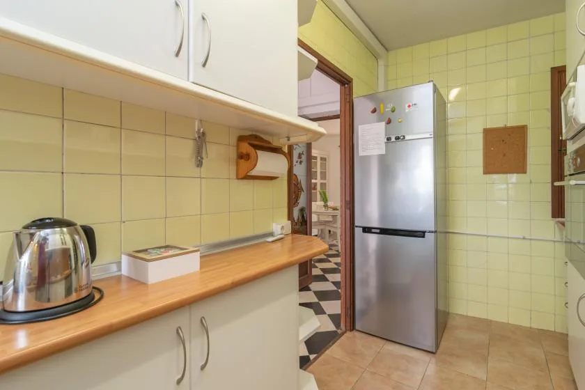 A tiled kitchen with a refrigerator and a long countertop.