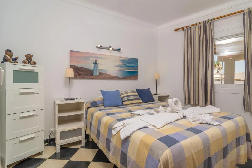 A bedroom with a double bed dressed in a blue and yellow checkered bedspread.