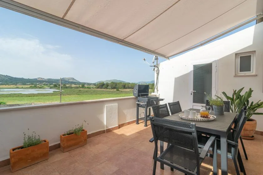 Covered terrace with outdoor dining seating and a view across the surrounding landscape.