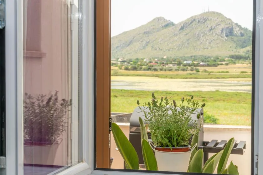 An open doorway frames potted plants and outdoor seating with a mountain landscape beyond.