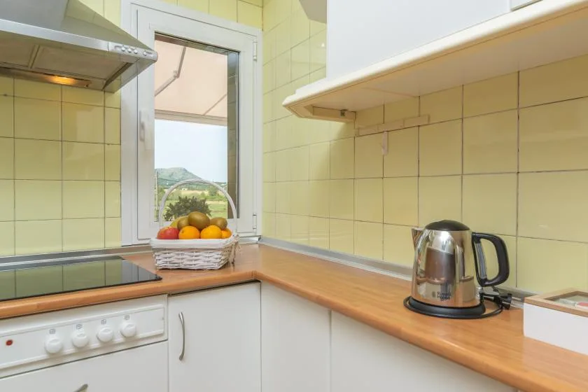 A tiled kitchen with wooden countertops, a stovetop, and a kettle.