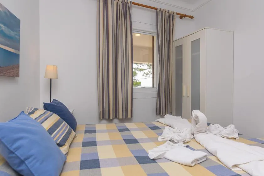 A bedroom with a bed covered in a blue, yellow, and gray checkered bedspread.