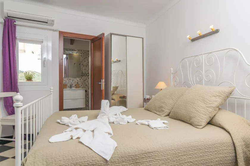 A bedroom with a neatly made bed and an open doorway to a bathroom.