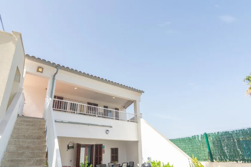 A white building exterior with an outdoor staircase and balcony under a clear sky.