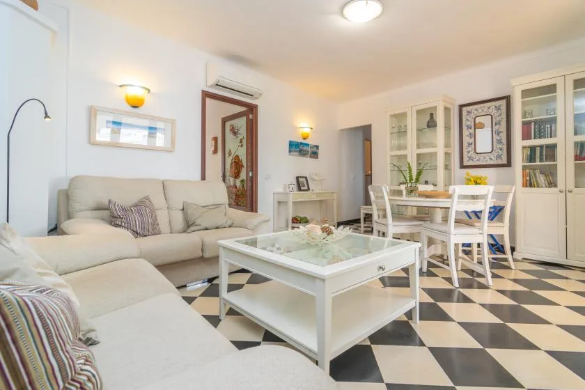 A bright living room has seating, a glass coffee table, and a dining area.
