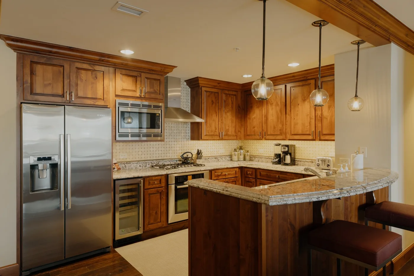 Una cocina con gabinetes de madera, una isla central y electrodomésticos de acero inoxidable.