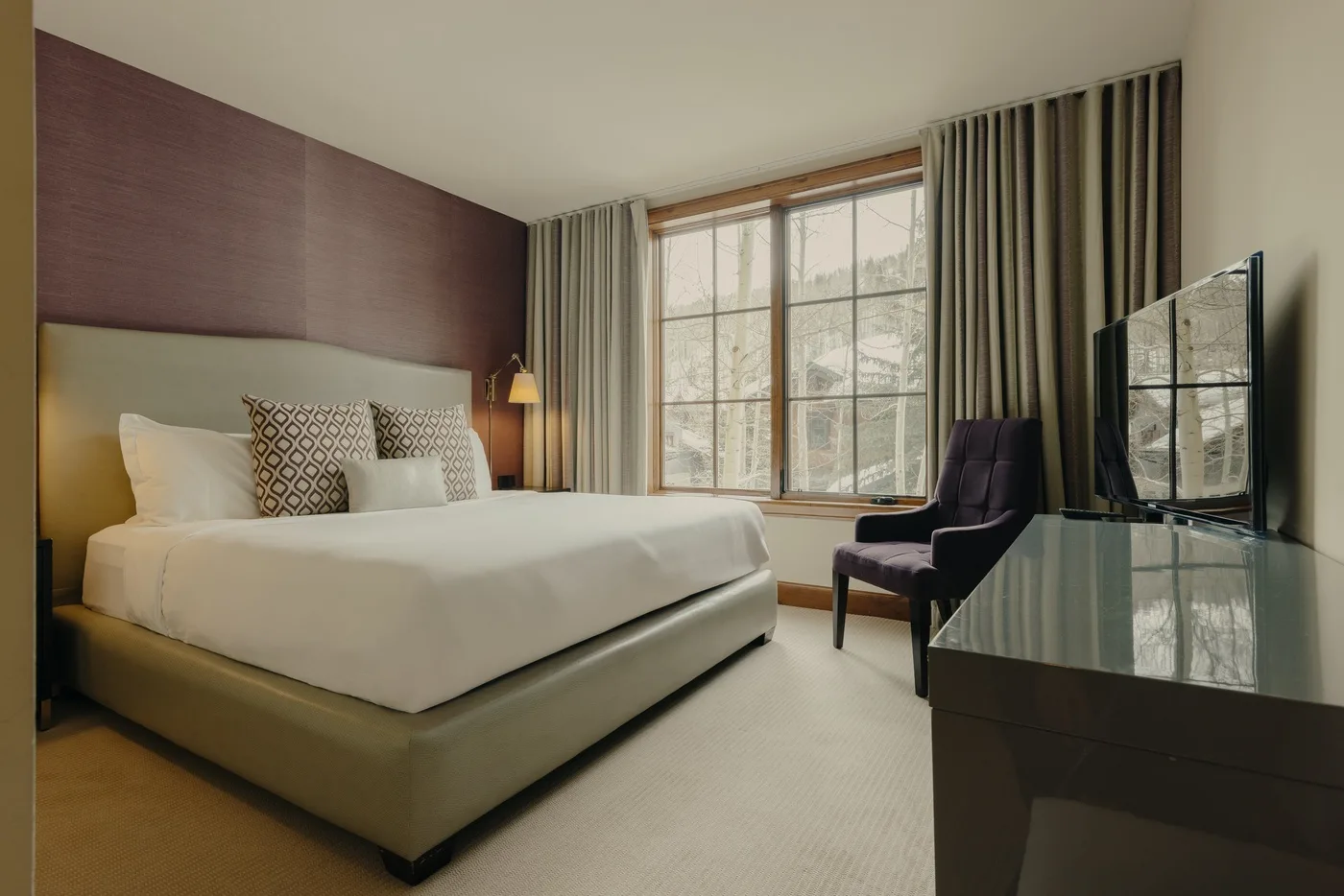 Un dormitorio con cama, una ventana grande y un televisor.