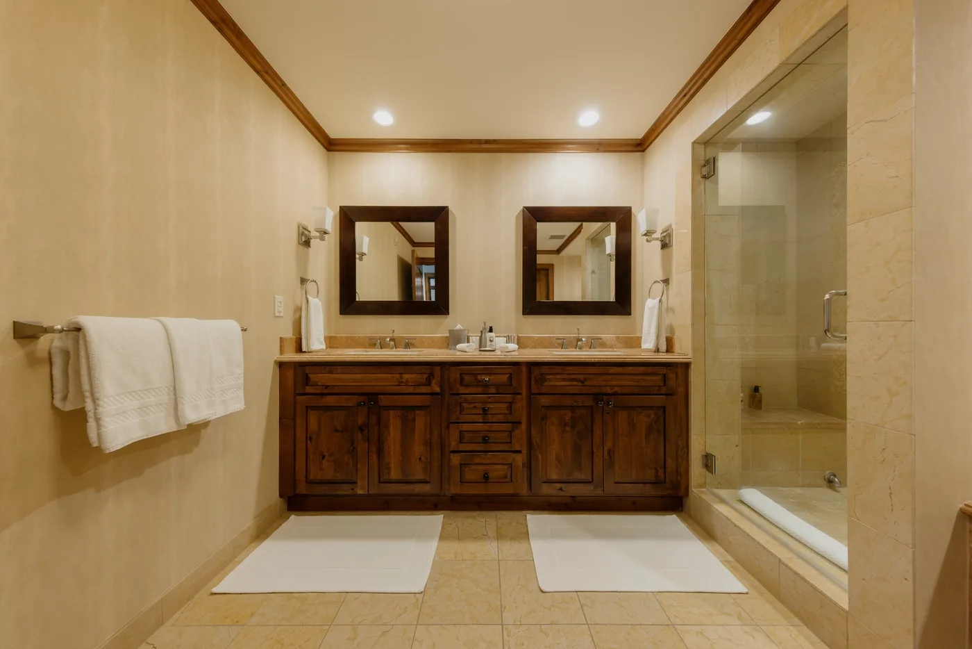 Un baño con un tocador doble de madera, espejos y una ducha de vidrio.