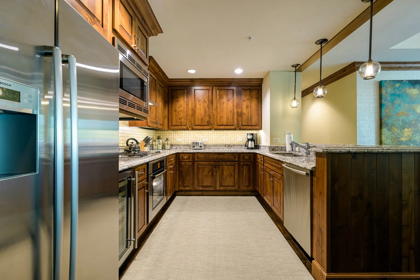 Una cocina con gabinetes de madera, electrodomésticos de acero inoxidable y una zona de trabajo central.