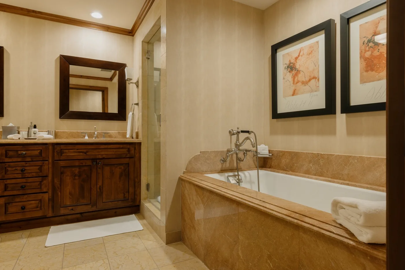 Un baño con un mueble de madera, bañera y cuadros enmarcados.