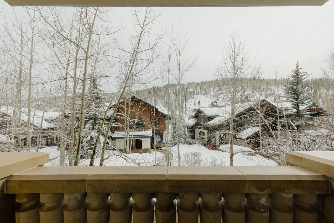 Se ven edificios cubiertos de nieve y árboles sin hojas desde una ventana.