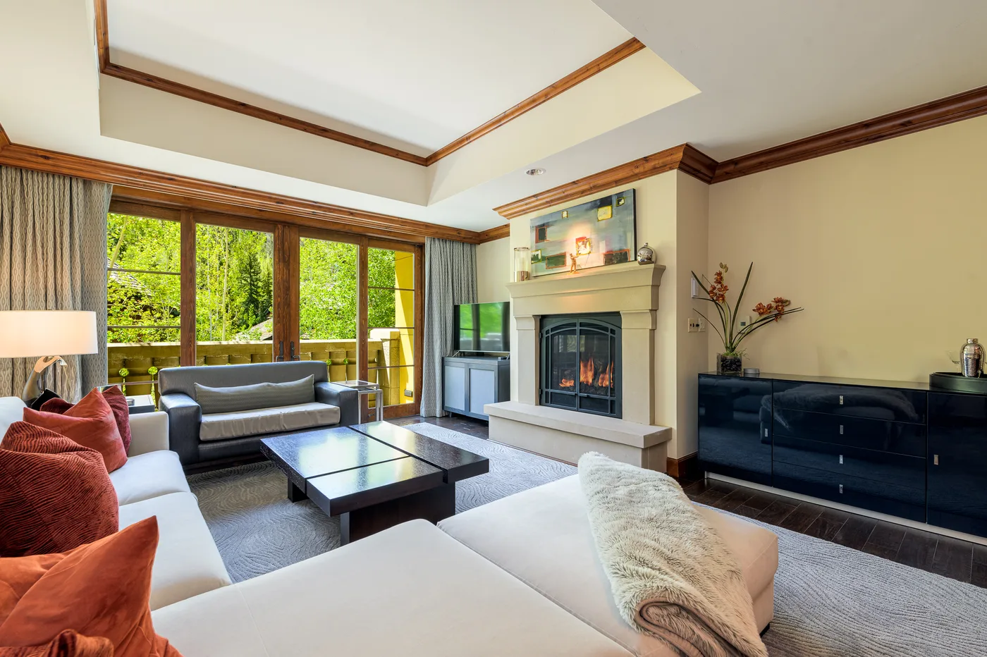 Una sala de estar con asientos, una mesa de centro y una chimenea junto a grandes ventanas.