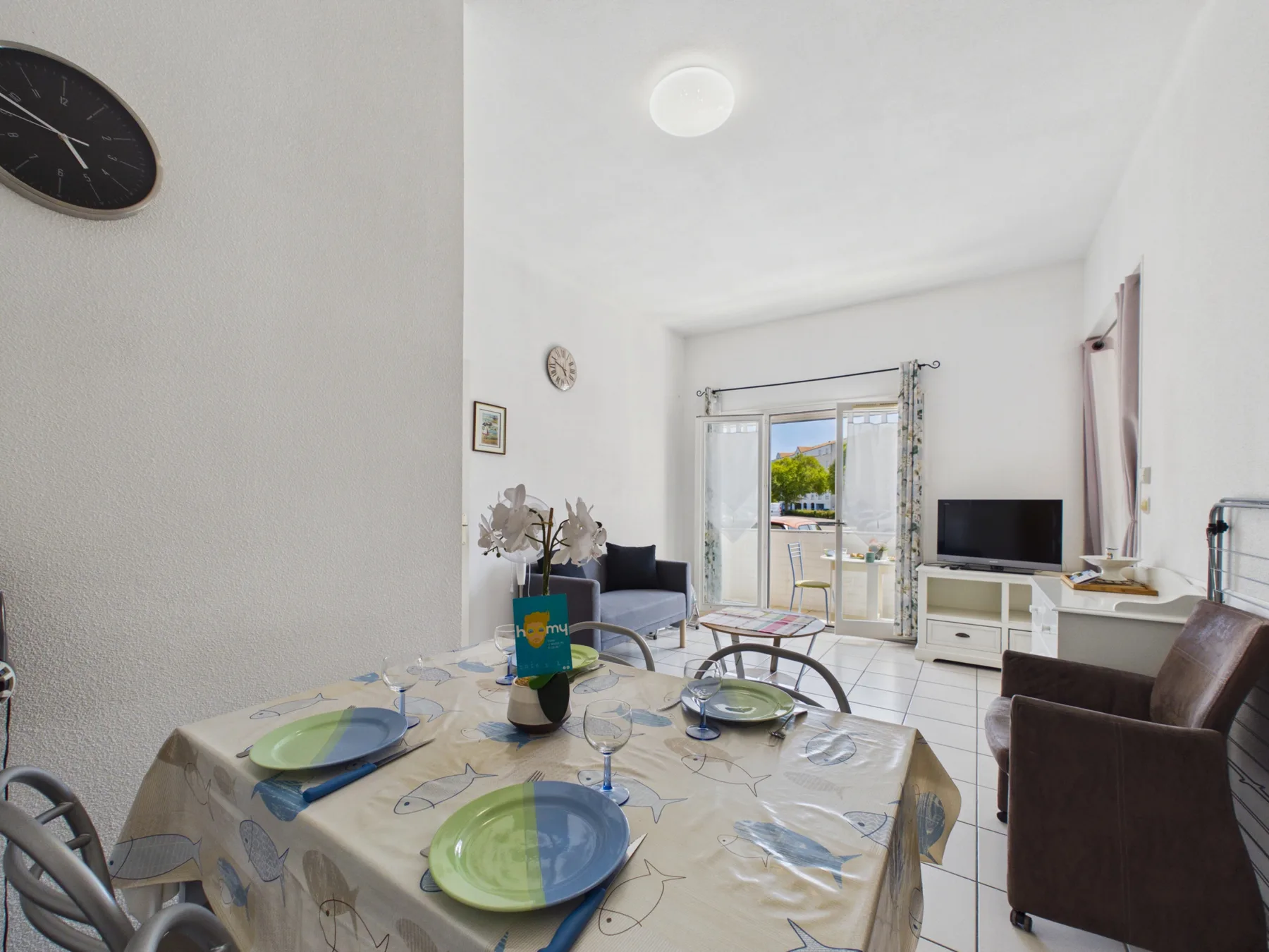 A bright living and dining area with a table set near the balcony doors.