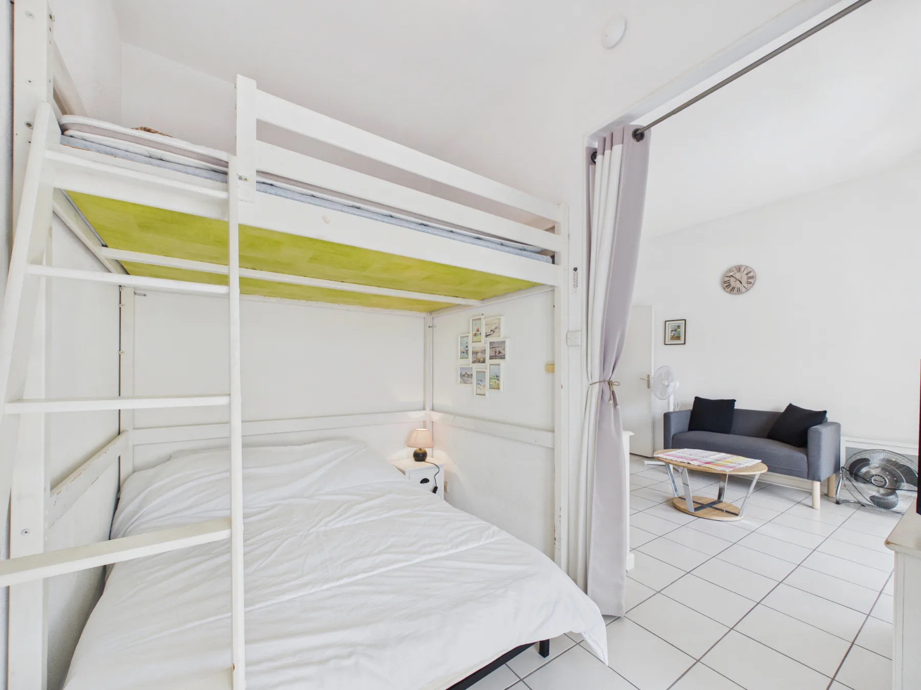 A bunk bed with white bedding sits beside a small tiled sitting area.