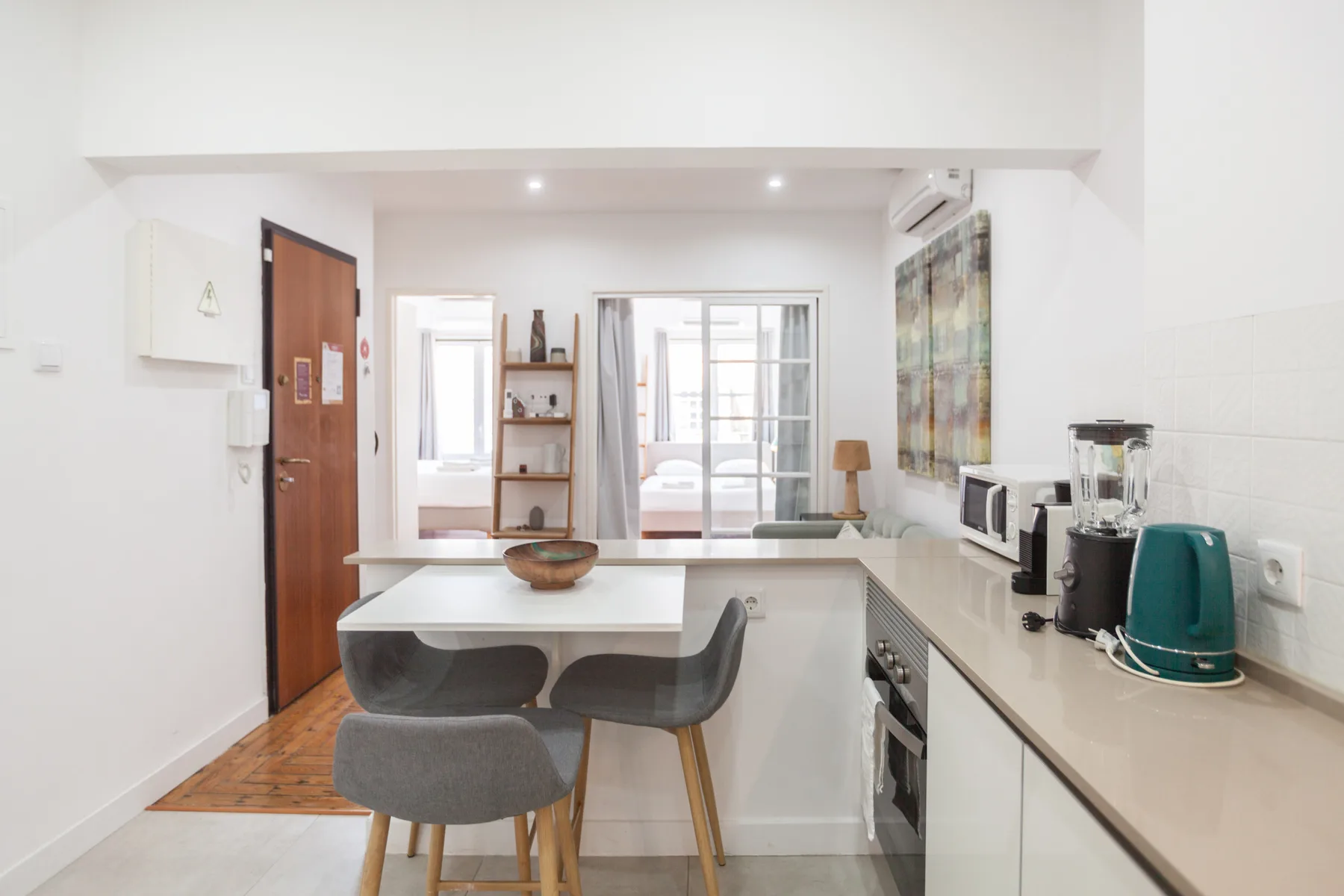 A bright kitchen with a counter, seating, and appliances along the wall.
