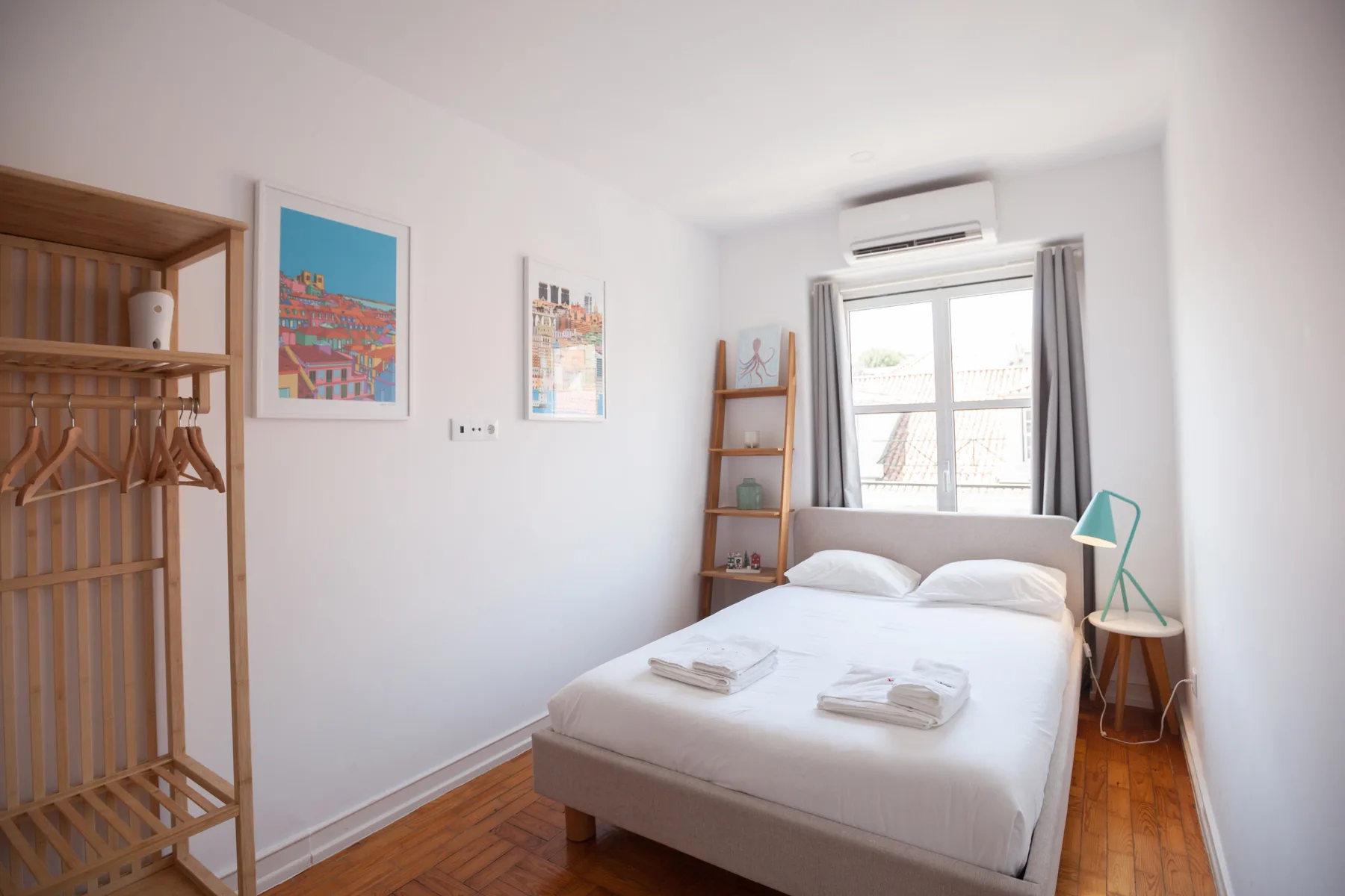 A bright bedroom with a bed, wall art, and a window.