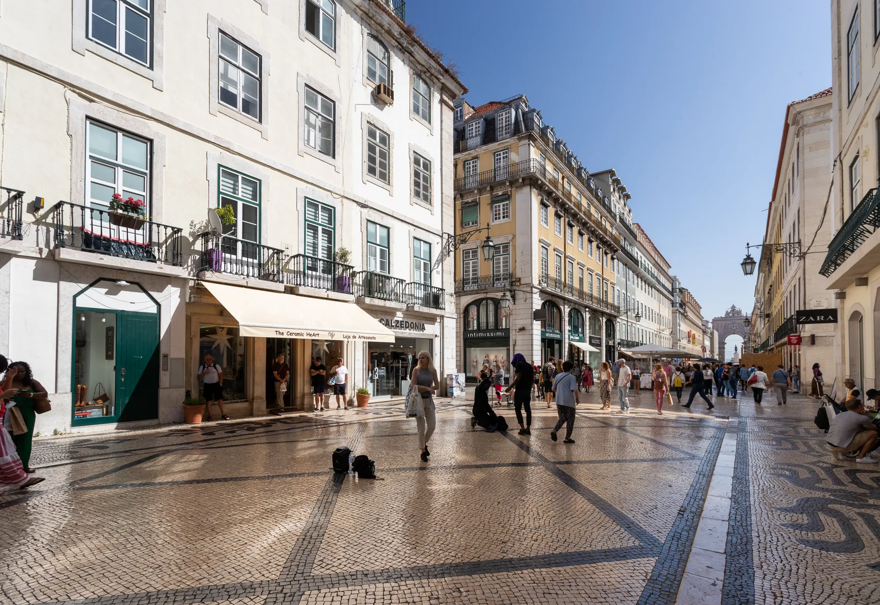 A pedestrian shopping street with patterned paving and people walking between buildings.