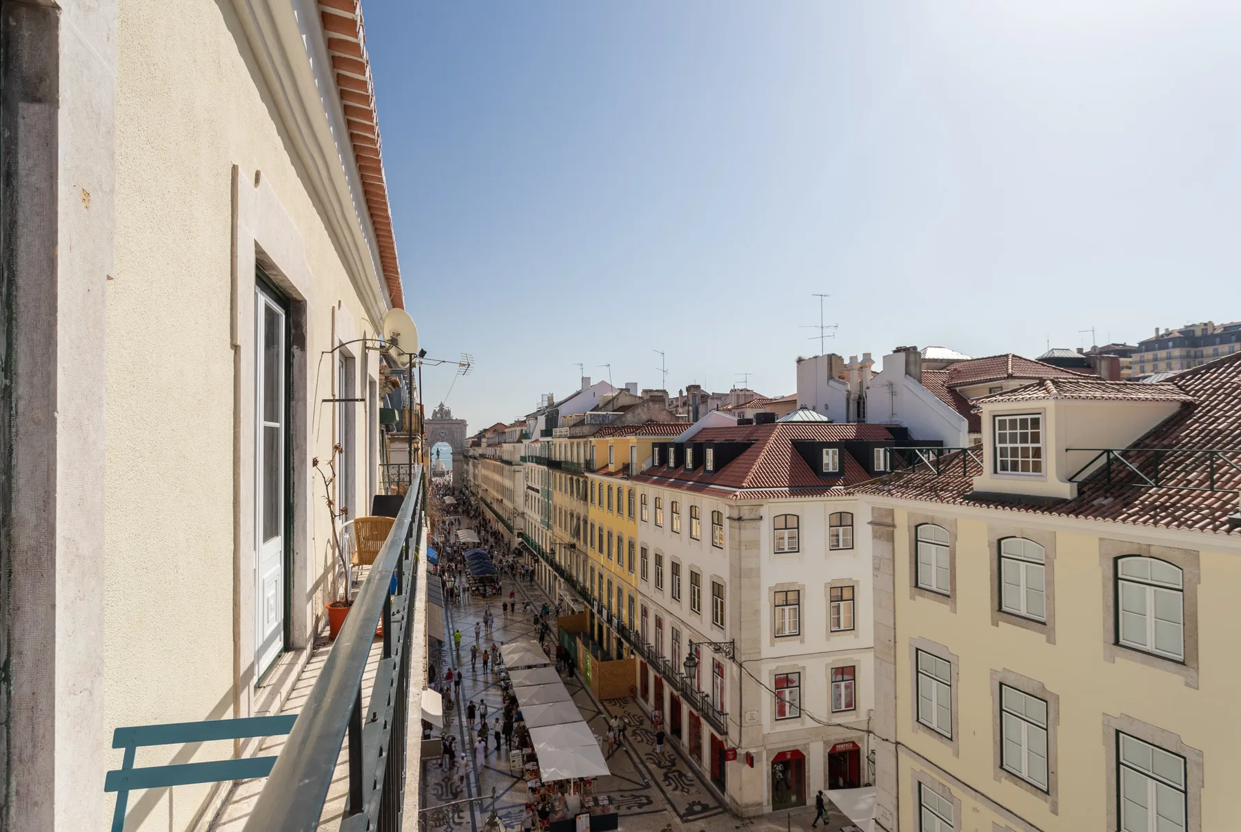 A balcony overlooks a narrow city street lined with buildings.