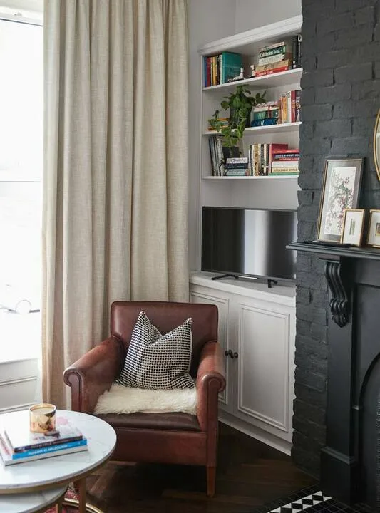 A living room corner with a leather armchair beside built-in shelves and a television.