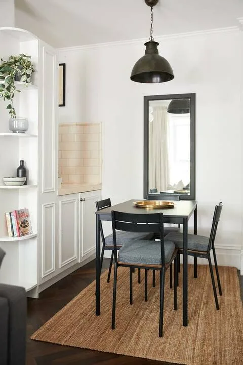 A dining area with a table and chairs on a woven rug.