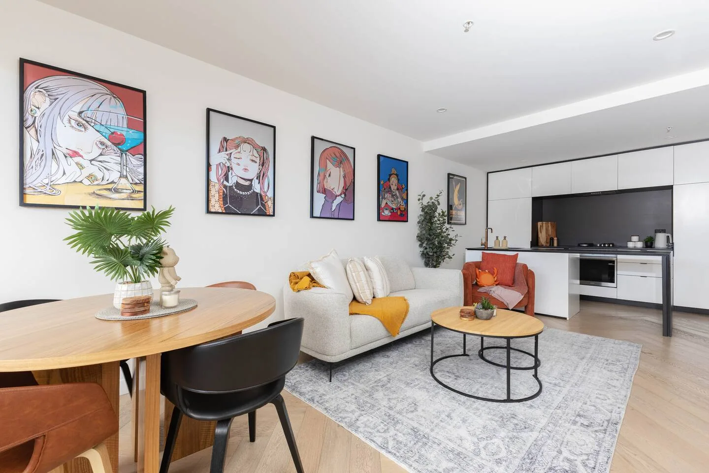 A bright living area with seating, framed artwork, and an open kitchen.