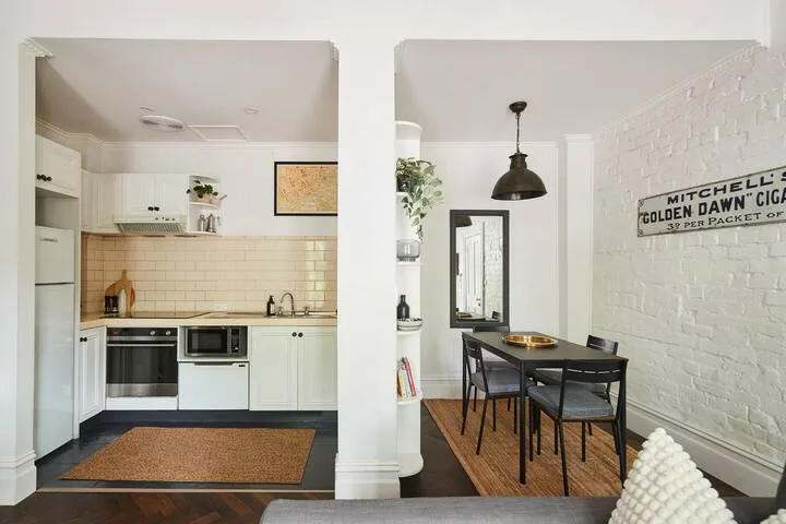 A bright kitchen and dining area with white cabinetry and a dark table.