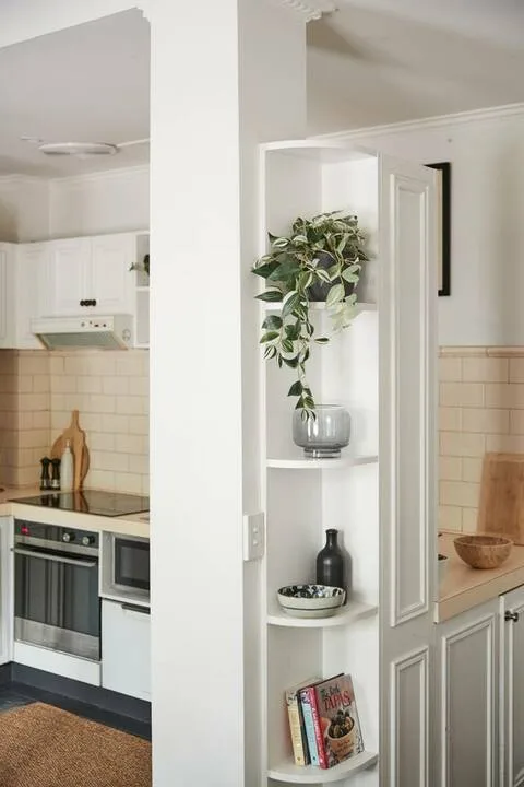 A bright kitchen with white cabinetry, tiled walls, and a built-in oven.