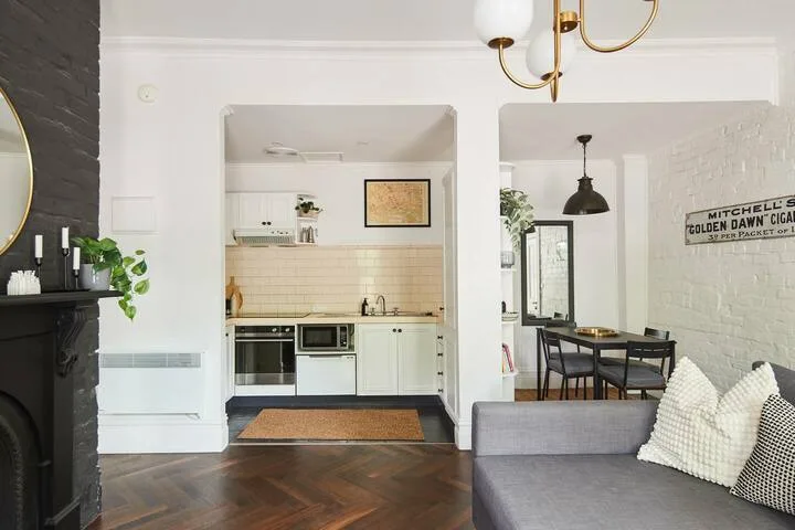 An open-plan living room and kitchen with dining seating and a gray sofa.