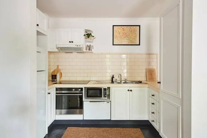 A bright white kitchen with tiled backsplash, built-in oven, and countertop.