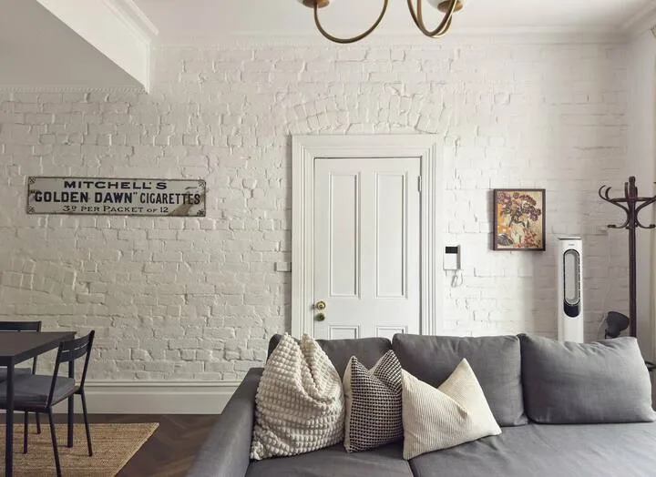 A living room with gray seating and a white brick wall.