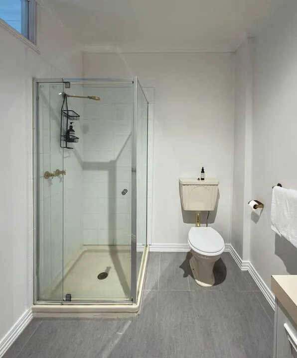 A bright bathroom with a glass shower and toilet.