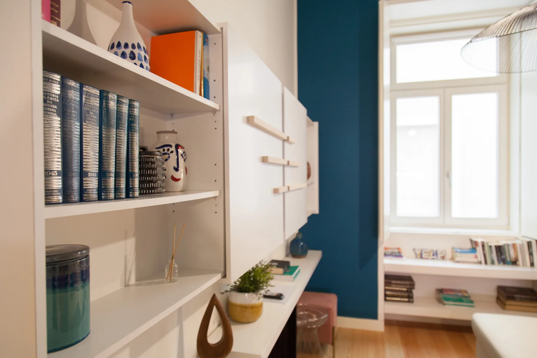 Una habitación luminosa con estanterías empotradas, libros y una ventana.