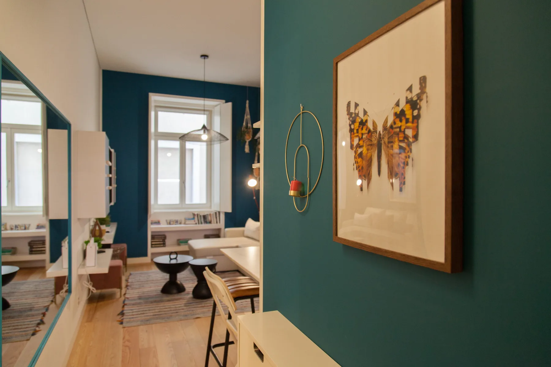 Una sala de estar con paredes verde azulado, un sofá y una obra enmarcada.