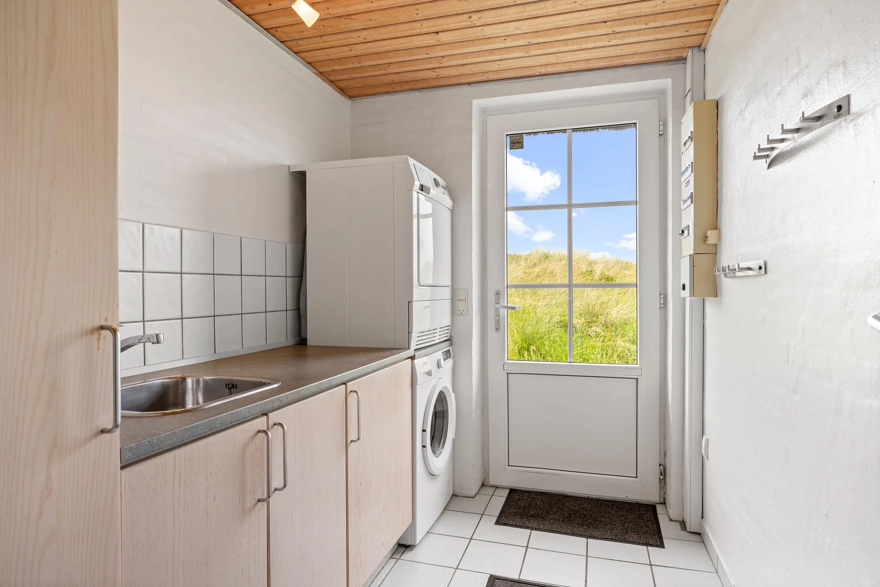 A compact utility room with a sink, washing machine, and glazed exterior door.