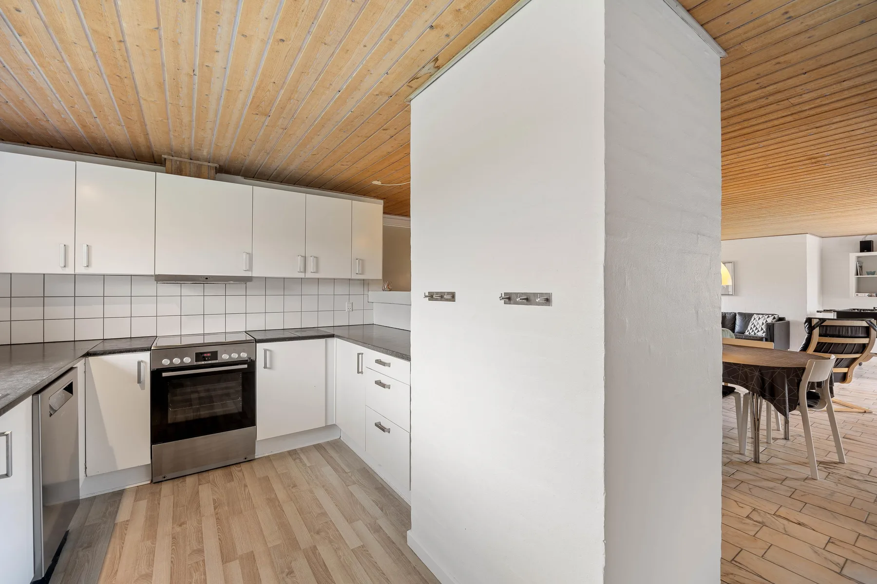 An open kitchen and dining area with white cabinets and a wooden ceiling.