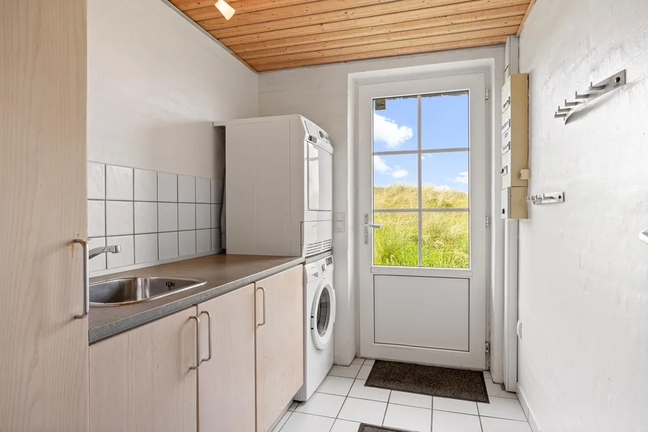 A compact kitchen with pale cabinets and a glazed door opening onto a green view.