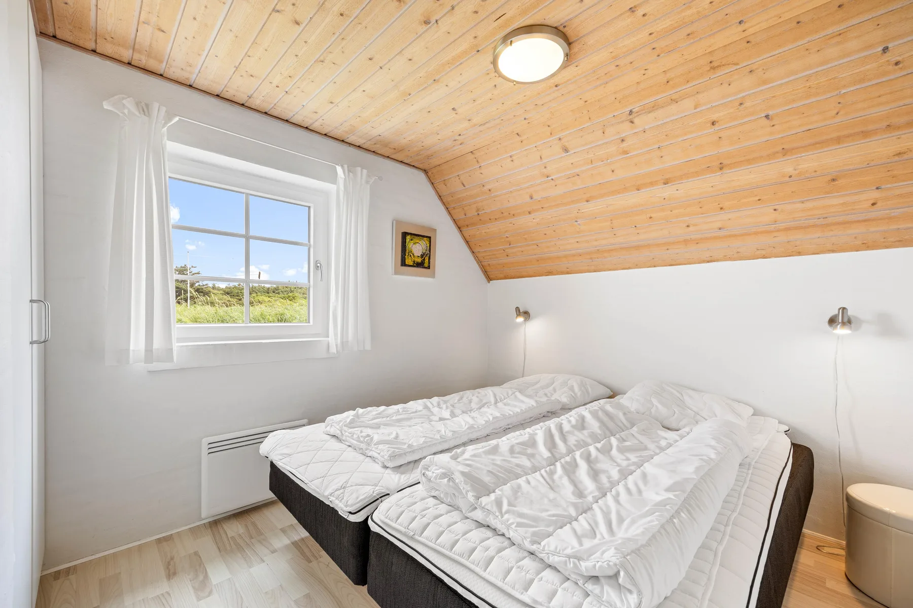 A bedroom with two beds beneath a sloped wooden ceiling.
