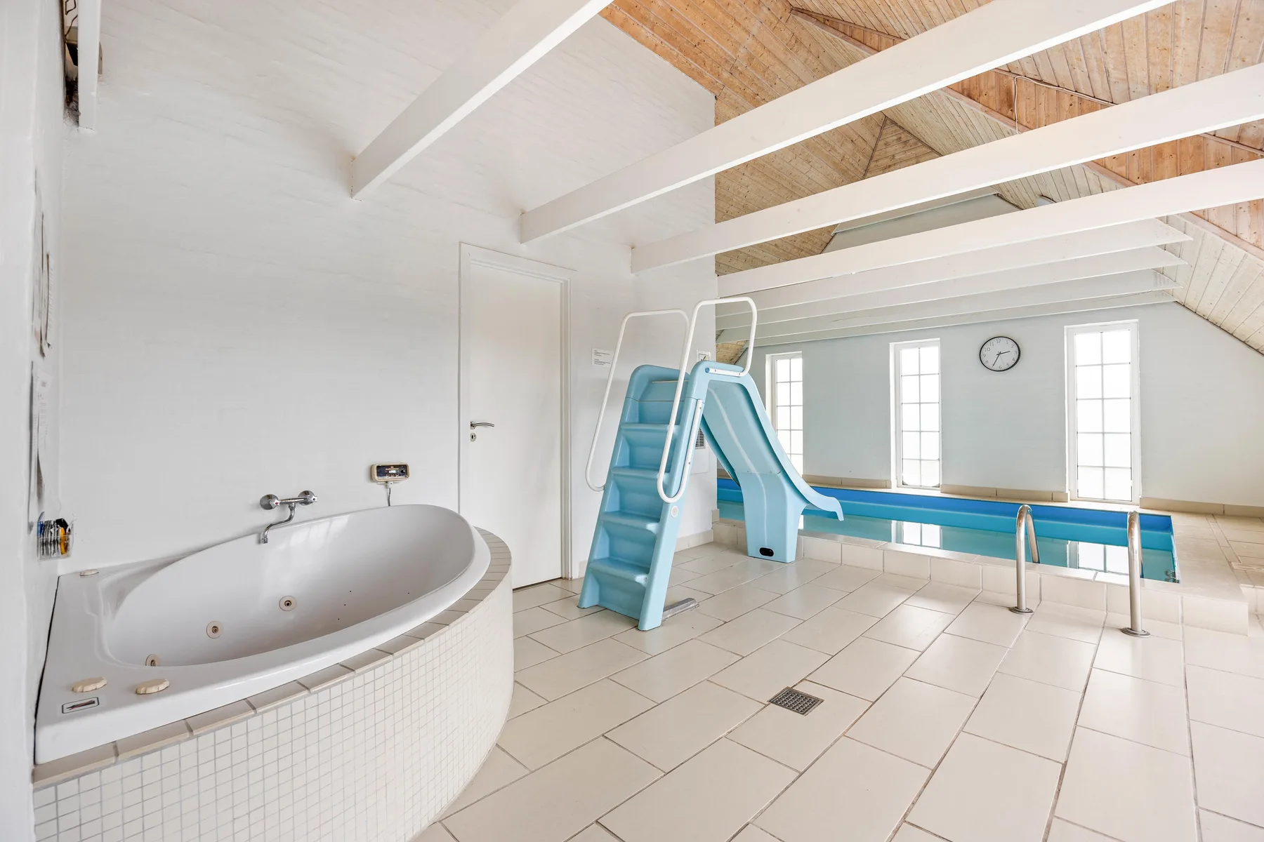 An indoor pool room with a waterslide and a large bathtub.